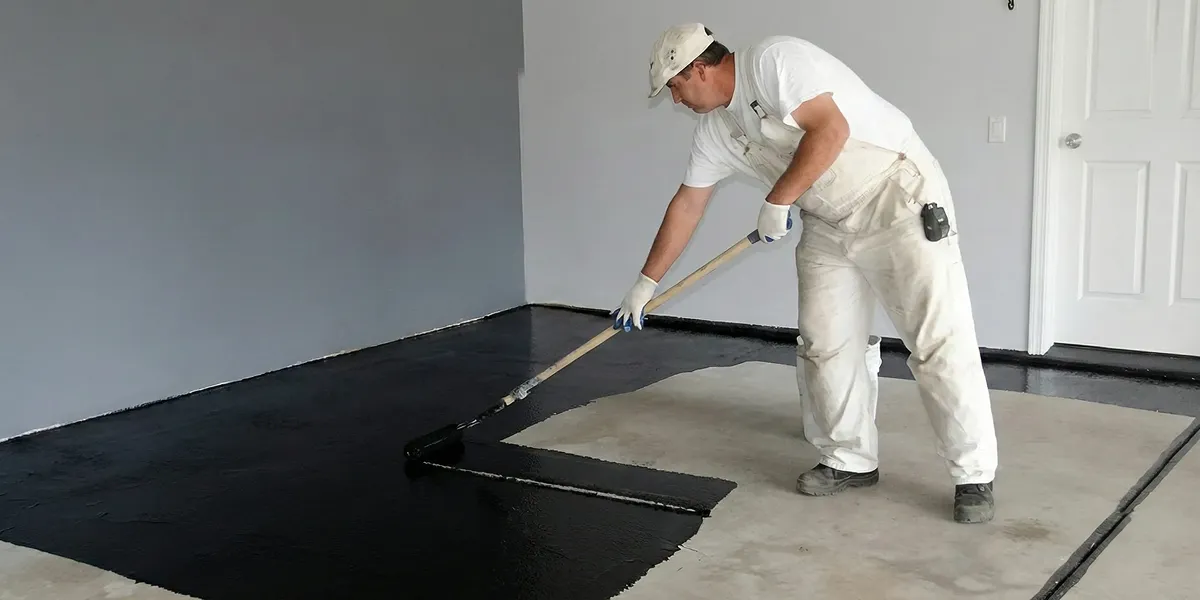 basement waterproofing professional applying waterproof coating to protect a basement floor in Wichita, KS